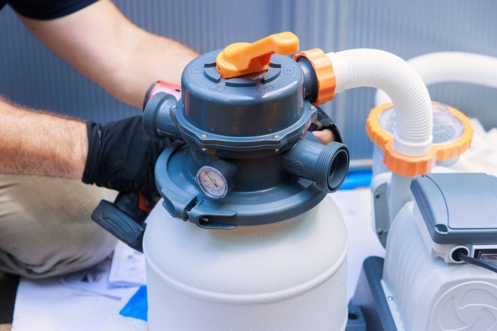 Worker assembling a sand filter system tank, equipment for cleaning swimming pools